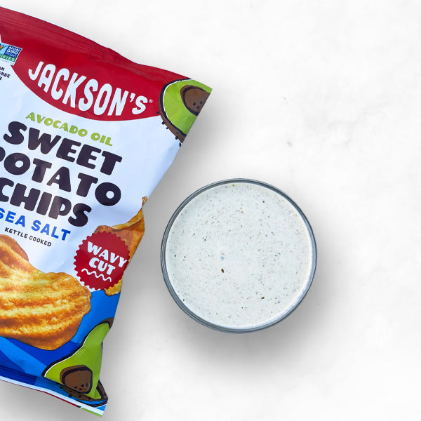 A bag of Jackson's Sea Salt Wavy Sweet Potato Chips next to a bowl of dipping sauce.