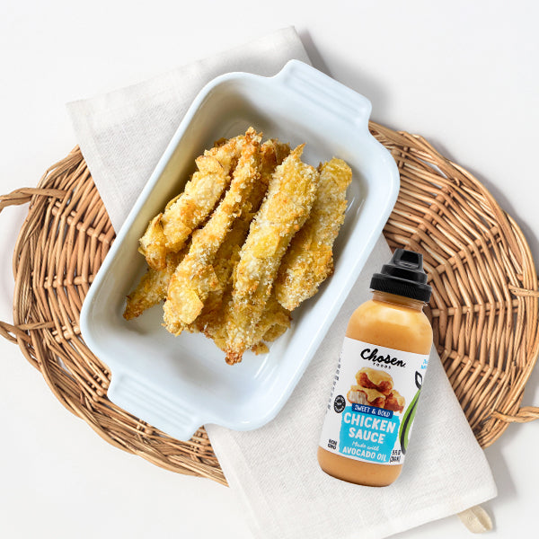 Potato chip crusted chicken fries next to a bottle of Chosen Foods Chicken Sauce