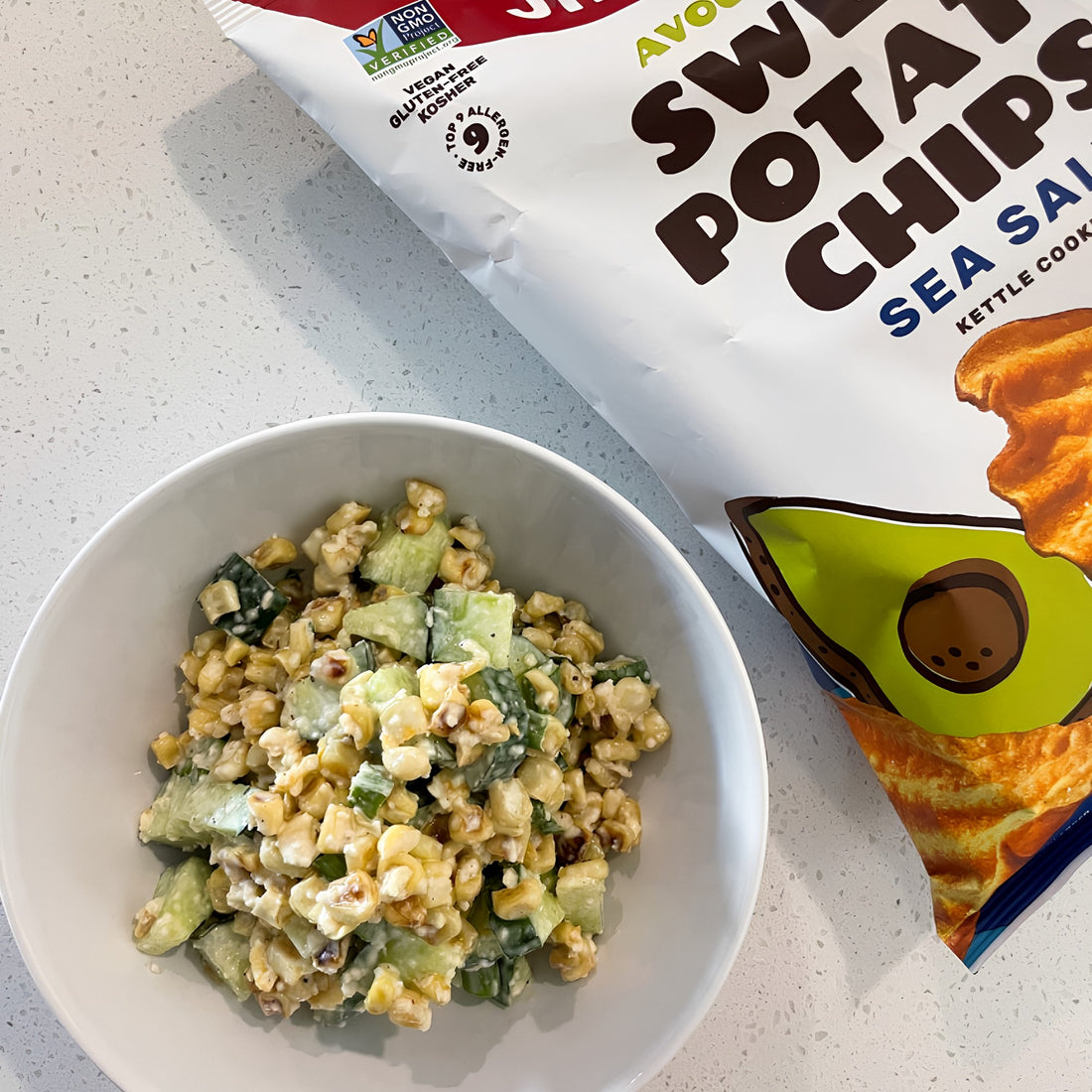 Corn salad in a bowl with Jackson's Sweet Potato Chips on the side