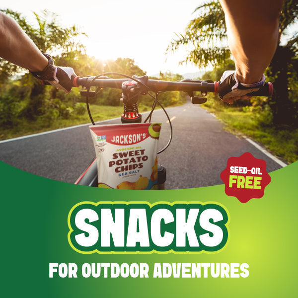 Person riding a bike outdoors with a bag of Jackson's Sweet Potato Chips made with avocado oil for on-the-go adventures