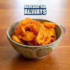 A ceramic bowl filled with golden-brown potato chips on a wooden table, with the text 'AVOCADO OIL ALWAYS' overlaid at the top.