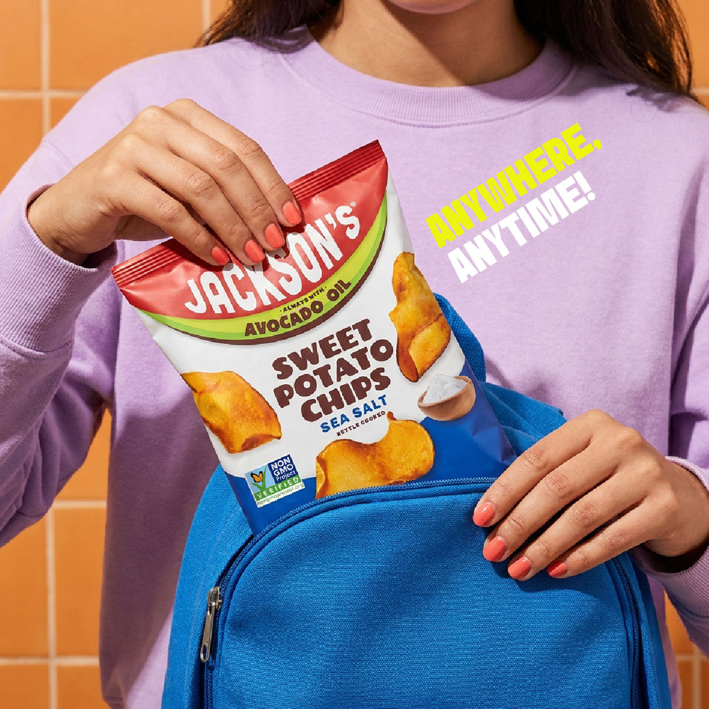 A person in a lavender sweatshirt places a bag of Jackson's Sweet Potato Chips into a bright blue backpack, with the text 'ANYWHERE. ANYTIME!' overlaid on the image.