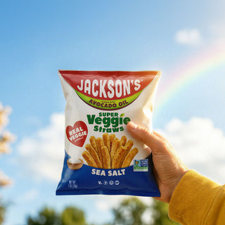 hand holding a bag of super veggie straws  with rainbow in the background
