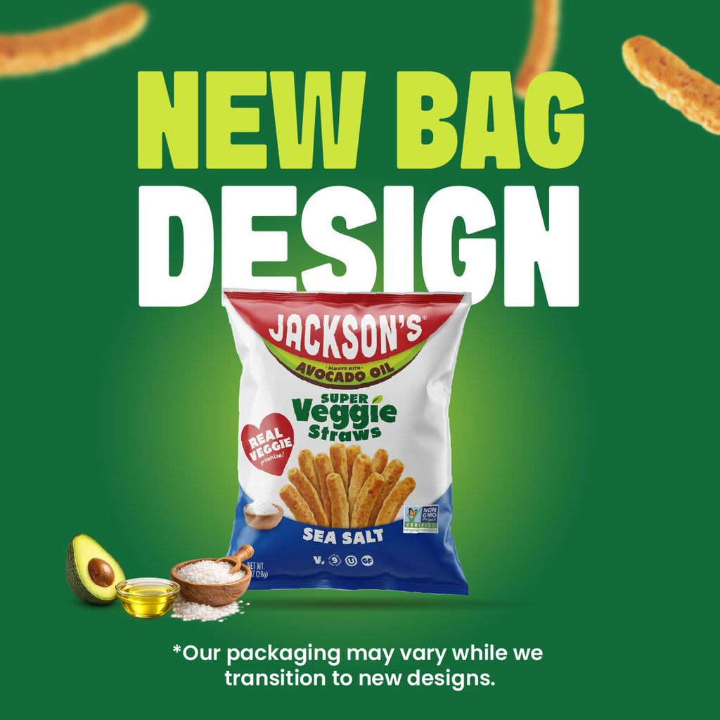A bag of Jackson's Veggie Straws Sea Salt Avocado Oil chips centered on a green promotional background with large text reading 'NEW BAG DESIGN.' The package is white with red, yellow, and blue branding, and small food props including an avocado half, a bowl of salt, and a small bowl of oil appear near the lower left.