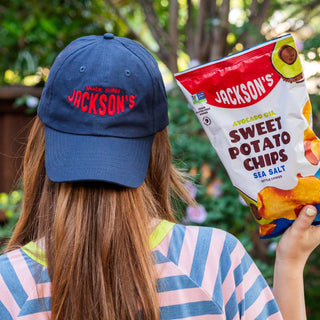 Jackson's Snack Super Ball Cap Hat. Navy Blue with Red stitching. Big bag of sweet potato chips in hand.