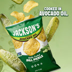 A bag of Jackson's Kettle Cooked Dill Pickle potato chips floating among illustrated whole cucumbers on a light green background, with the text 'COOKED IN AVOCADO OIL' at the top right.