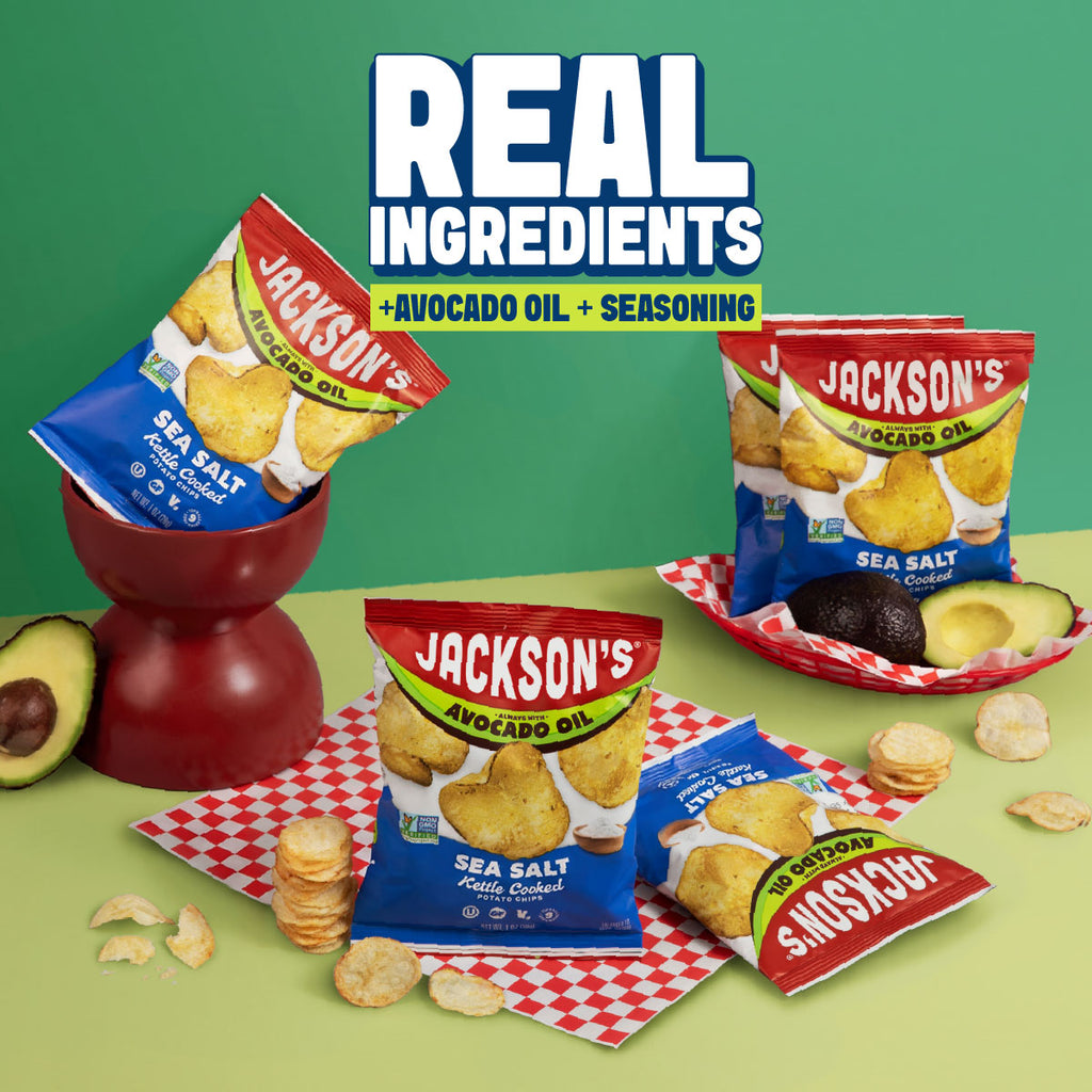 Snack-size bags of jackson's on a green surface with bowls, and trays and avocado, and checkered paper. Phrase real ingredients + avocado oil + seasoning