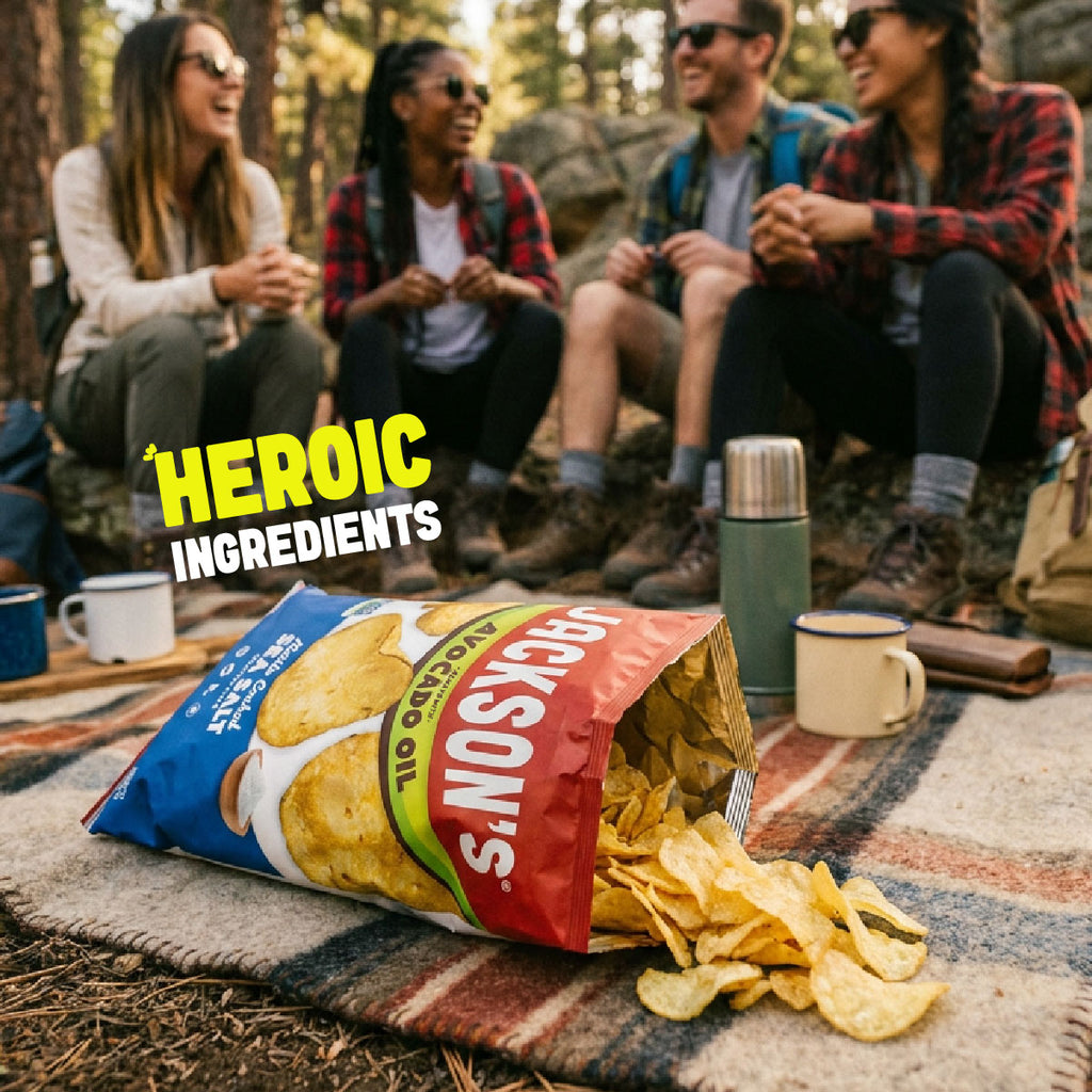 A bag of Jackson's Loaded Potato Chips lies open on a picnic blanket outdoors, with chips spilling out. Three friends are sitting behind it in a wooded setting, and the text 'HEROIC INGREDIENTS' appears on the left.